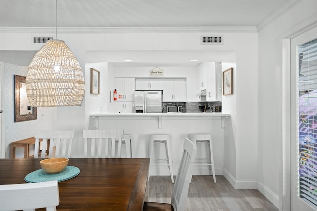 dining space with ornamental molding, breakfast area, and light hardwood / wood-style flooring