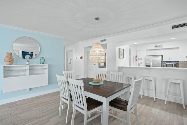 dining area featuring light hardwood / wood-style flooring and crown molding