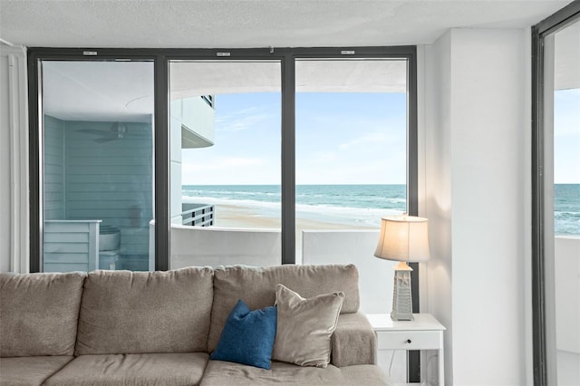 living room featuring a textured ceiling, a view of the beach, and a water view