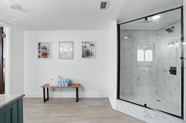 bathroom featuring vanity, a textured ceiling, and a shower with shower door