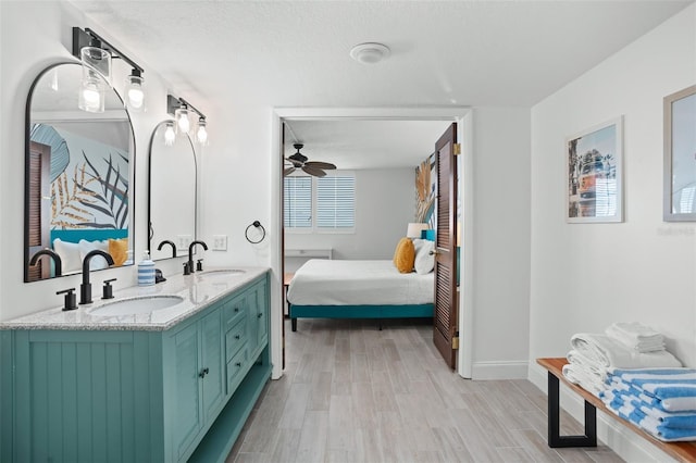 bathroom with ceiling fan, a textured ceiling, vanity, and wood-type flooring