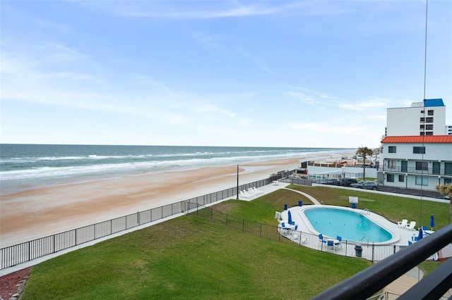 view of swimming pool featuring a beach view, a yard, and a water view