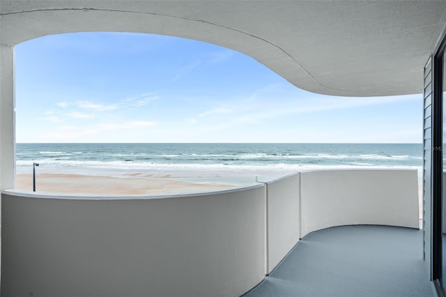 balcony featuring a view of the beach and a water view