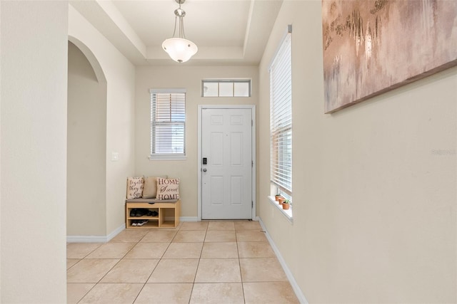 entrance foyer with light tile patterned flooring and a tray ceiling