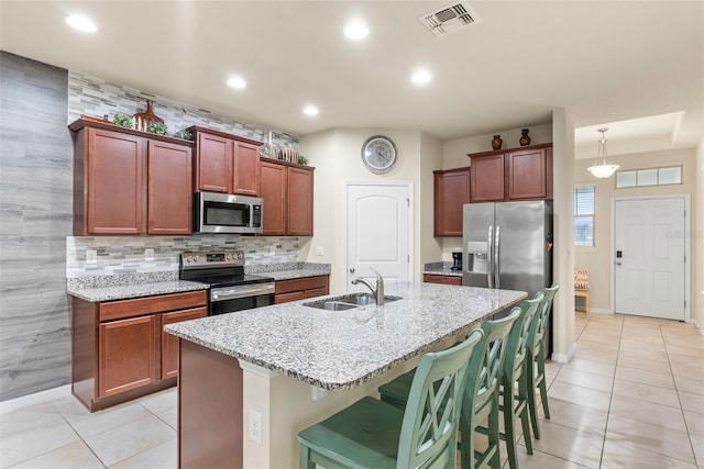 kitchen featuring light tile patterned floors, a breakfast bar, a kitchen island with sink, appliances with stainless steel finishes, and sink