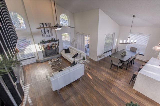 living room featuring a high ceiling, ceiling fan with notable chandelier, and dark hardwood / wood-style floors