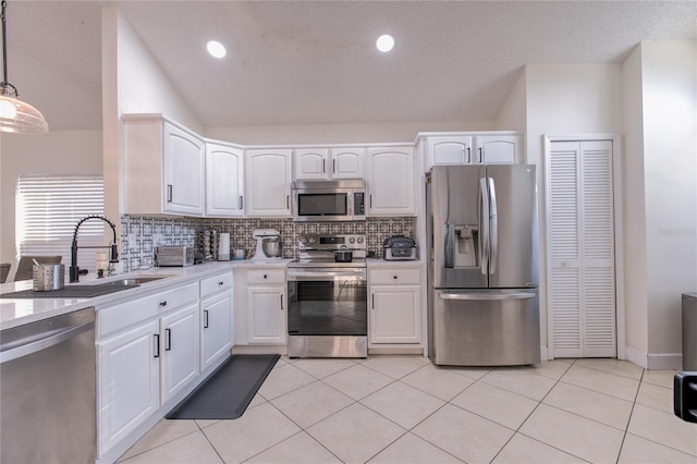 kitchen with white cabinets, appliances with stainless steel finishes, pendant lighting, and sink