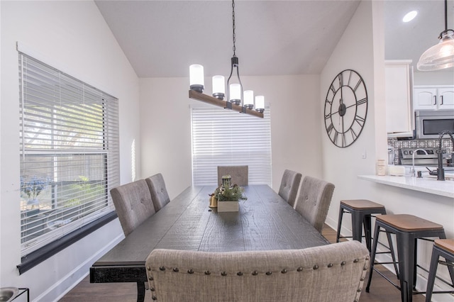 dining room featuring a notable chandelier, lofted ceiling, and hardwood / wood-style flooring