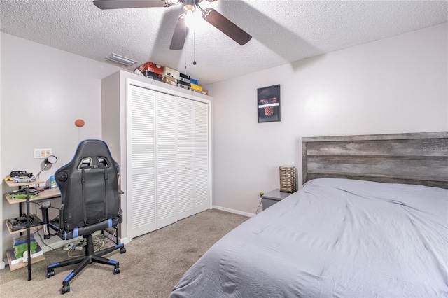 bedroom featuring ceiling fan, light colored carpet, a closet, and a textured ceiling