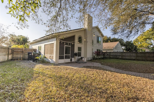 back of property with a yard and a sunroom