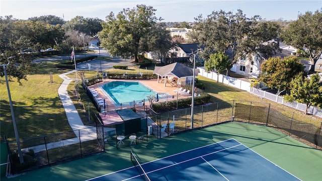 view of tennis court with a yard and a fenced in pool