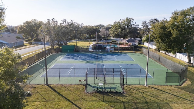 view of tennis court featuring a yard