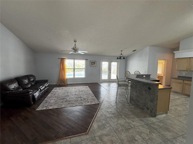 living room with ceiling fan, french doors, lofted ceiling, and a textured ceiling