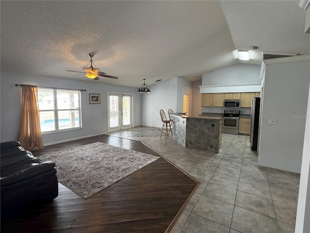 living room with a textured ceiling, vaulted ceiling, french doors, ceiling fan, and light tile patterned flooring