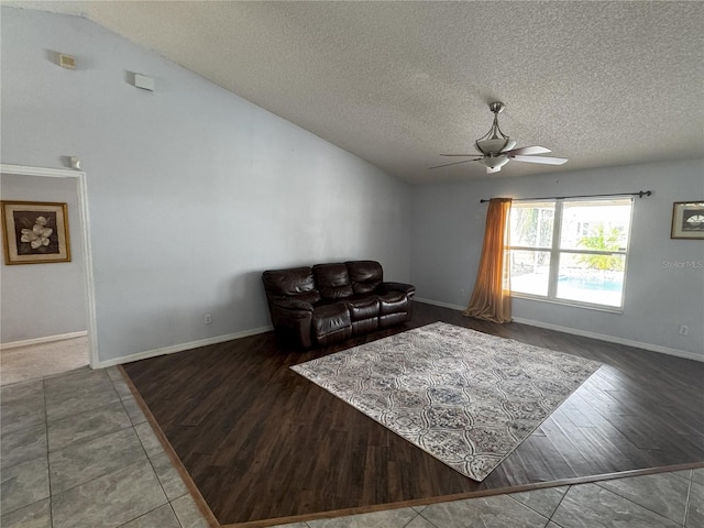 living room with a textured ceiling, ceiling fan, vaulted ceiling, and dark tile patterned flooring