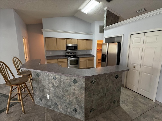 kitchen featuring appliances with stainless steel finishes, a kitchen bar, a kitchen island, a textured ceiling, and lofted ceiling