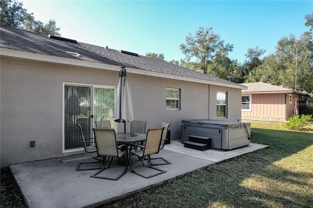 back of property featuring a lawn, a patio area, and a hot tub