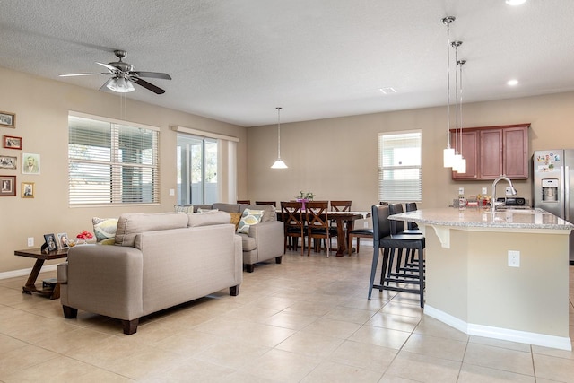 living room featuring a textured ceiling, ceiling fan, a healthy amount of sunlight, and sink