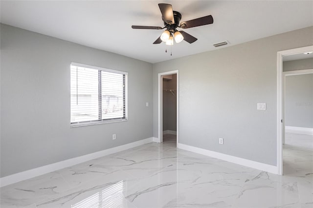 unfurnished bedroom with a spacious closet, a closet, and ceiling fan