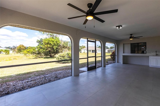 unfurnished sunroom featuring ceiling fan