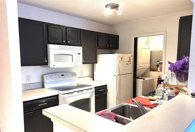 kitchen with white appliances, stacked washing maching and dryer, and sink