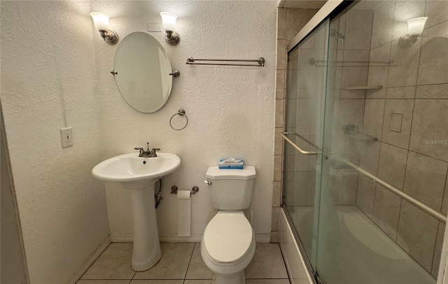 full bathroom with sink, tile patterned flooring, bath / shower combo with glass door, and toilet