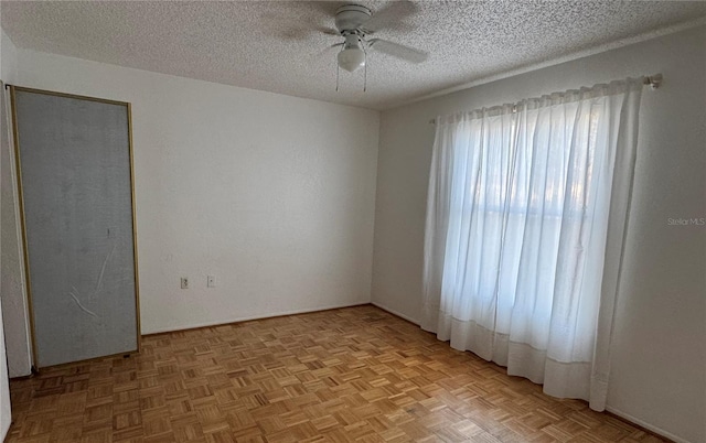 empty room with light parquet flooring, ceiling fan, and a textured ceiling