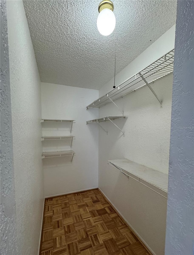 walk in closet featuring dark parquet flooring