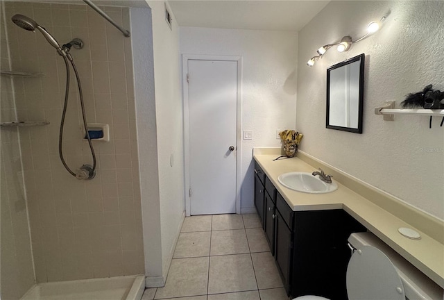 bathroom with tiled shower, vanity, tile patterned floors, and toilet