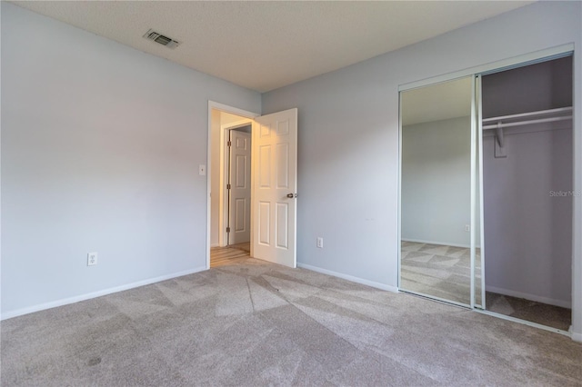 unfurnished bedroom with light colored carpet and a closet