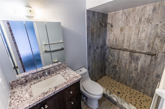 bathroom featuring a tile shower, vanity, and toilet