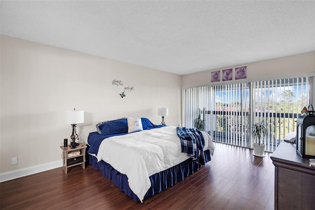 bedroom featuring access to outside, a textured ceiling, and dark hardwood / wood-style floors