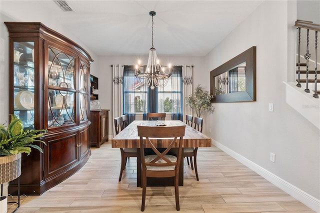 dining area with light hardwood / wood-style floors and a chandelier