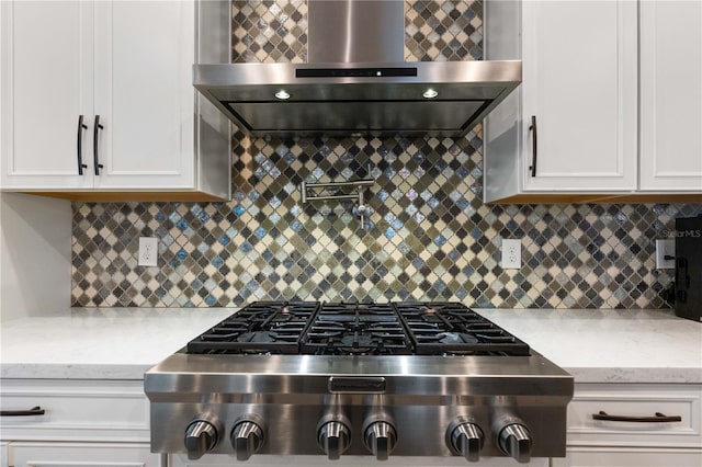 kitchen featuring stainless steel gas stovetop, white cabinetry, backsplash, and wall chimney exhaust hood