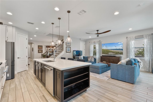 kitchen featuring hanging light fixtures, stainless steel appliances, a center island with sink, white cabinetry, and sink