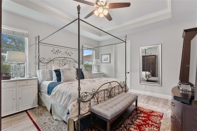 bedroom with a raised ceiling, ceiling fan, light hardwood / wood-style floors, and crown molding