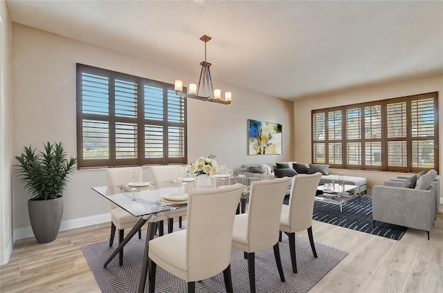 dining room with a healthy amount of sunlight, light wood-type flooring, and a notable chandelier