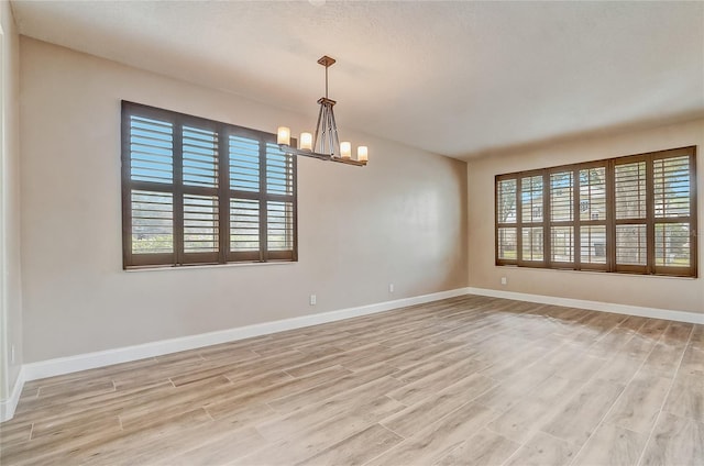 spare room featuring light hardwood / wood-style flooring and a notable chandelier