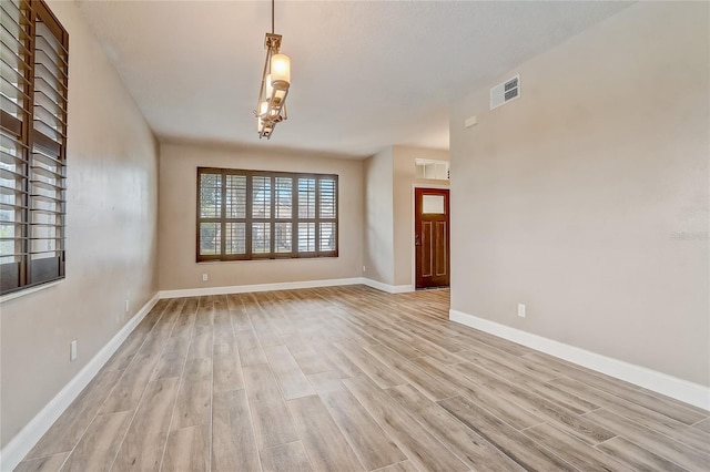 unfurnished room featuring light hardwood / wood-style flooring and a chandelier