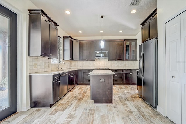 kitchen with stainless steel appliances, dark brown cabinetry, hanging light fixtures, and a center island