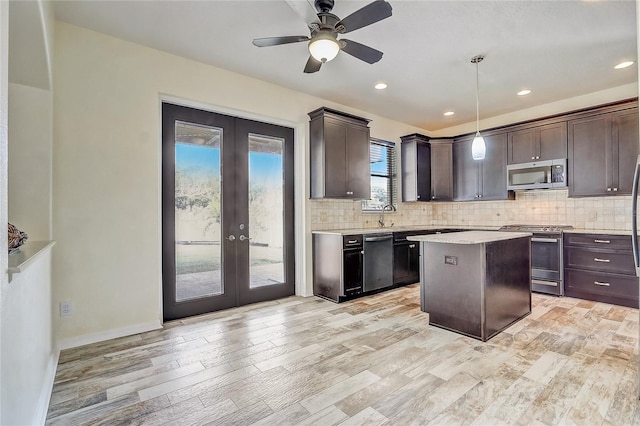 kitchen with appliances with stainless steel finishes, dark brown cabinets, french doors, hanging light fixtures, and a center island