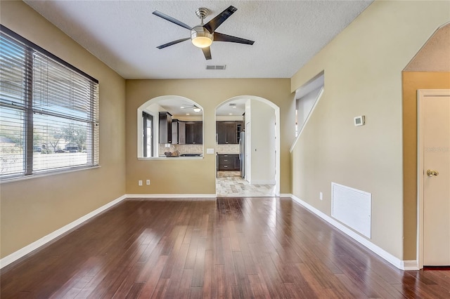 empty room with ceiling fan, a textured ceiling, and hardwood / wood-style flooring