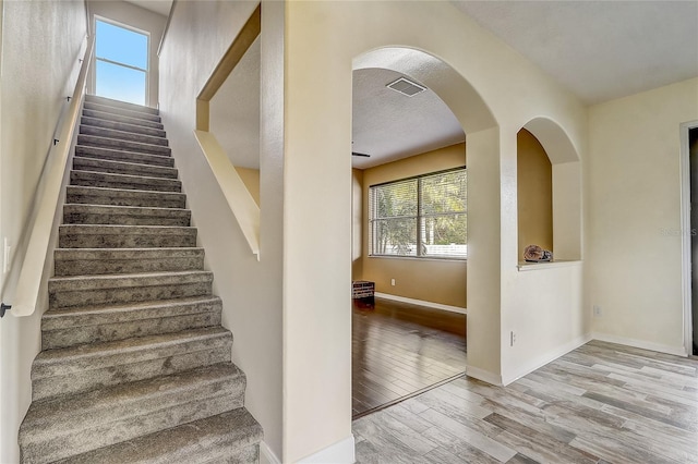 stairs with a textured ceiling and hardwood / wood-style floors