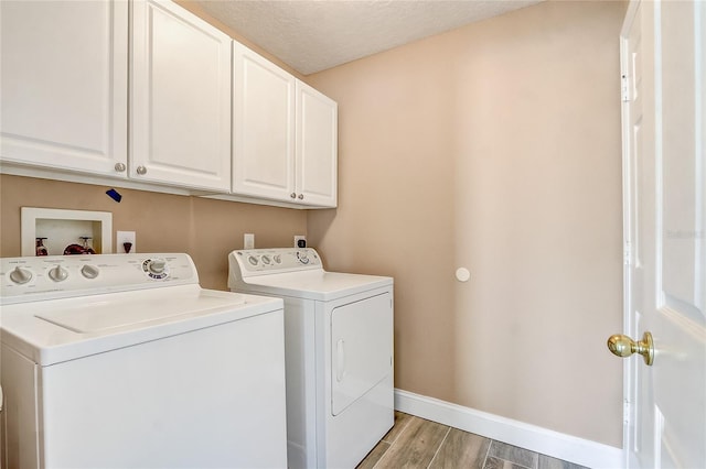 laundry area with separate washer and dryer, a textured ceiling, and cabinets