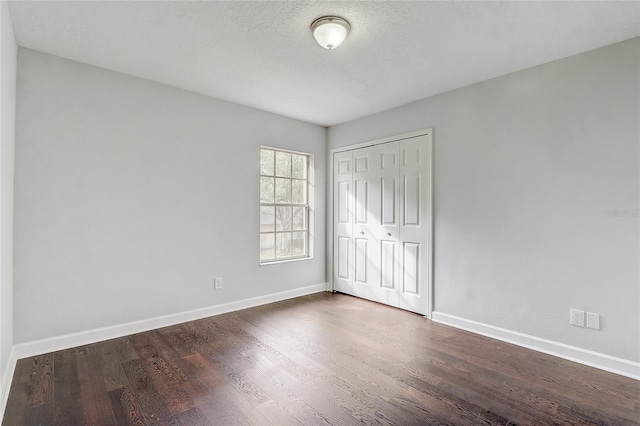 unfurnished bedroom with a closet and dark hardwood / wood-style floors