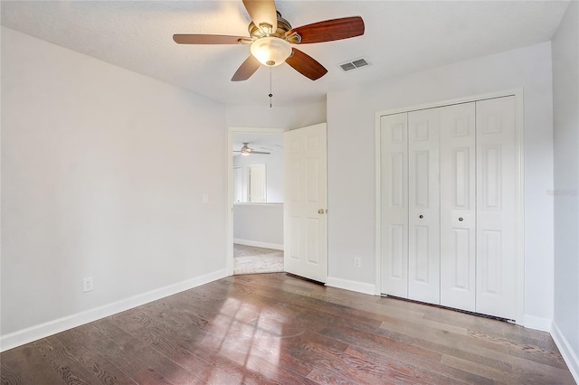 unfurnished bedroom with ceiling fan, dark hardwood / wood-style floors, and a closet