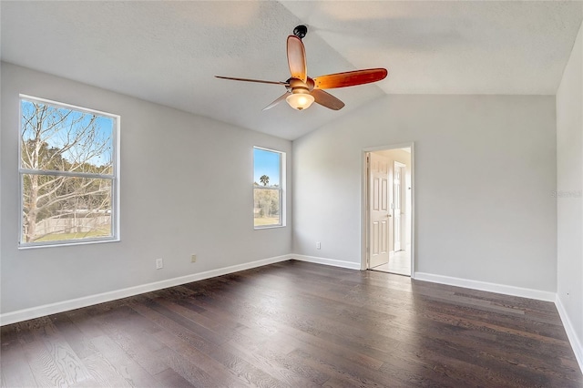 empty room featuring ceiling fan, a wealth of natural light, lofted ceiling, and dark hardwood / wood-style flooring