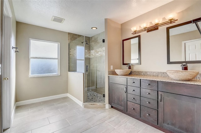 bathroom featuring a shower with shower door, a textured ceiling, vanity, and tile patterned flooring