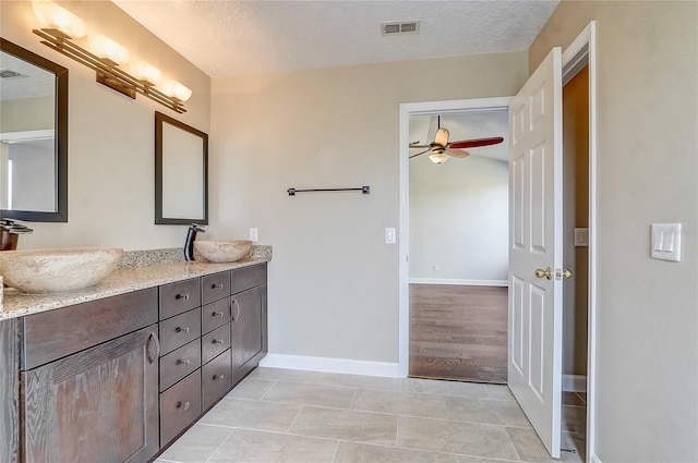 bathroom with a textured ceiling, ceiling fan, tile patterned flooring, and vanity