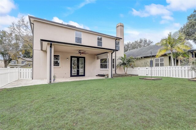 rear view of house with ceiling fan, french doors, a lawn, and a patio area